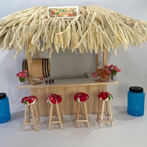 May include: A miniature tiki bar with a thatched roof, a wooden counter, and four red floral patterned bar stools. The bar is decorated with a sign that reads "Tiki Bar Aloha!" and has a barrel, flowers, and seashells on the counter.