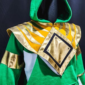 The MMPR Green Custom Hoodie Power Ranger blends cozy cotton fleece with bold vegan leather details. Each hoodie is made-to-measure based on your size, delivering a stylish tribute to the iconic Green Ranger—perfect for everyday wear or cosplay-ready comfort.
