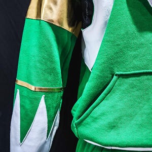 MMPR Green Hoodie designed for style-savvy fans who want comfort and character in one piece. The layered textures of fleece and vegan leather offer both warmth and a striking visual punch, ideal for cosplay, conventions, or daily wear with flair.