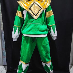 MMPR Green Hoodie crafted with soft cotton fleece and signature vegan leather overlays, delivering both warmth and an armored, tactical design. The sleek fit and bold styling make this a must-have for fans seeking to embody the spirit of the Green Ranger.