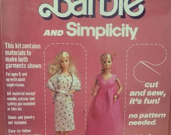 May include: A sewing kit featuring Barbie dolls wearing a pink gown and a floral dress. The kit includes fabric, thread, and instructions for making both garments. The packaging features the text "Begin to Sew with Barbie and Simplicity".