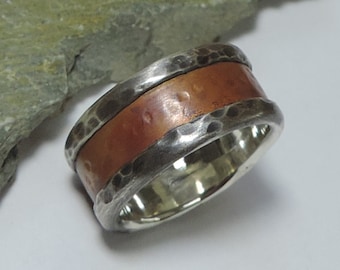 May include: A silver and copper band ring with a hammered texture. The copper band is set into the silver band.