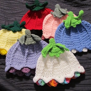 May include: Six crocheted hats in various colors, including red, pink, blue, yellow, purple, and white. Each hat has a crocheted flower on top and a scalloped edge.