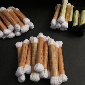 May include: A close-up of a pile of white shoelaces in brown cardboard packaging. The packaging has text that reads "Adult Shoe Lace 27 in./69 cm" and "Lacets Pour Adulte".