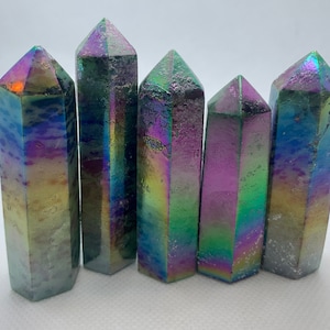 May include: Five iridescent titanium quartz crystal points, each with a unique pattern of colours, including green, blue, purple, and gold. The crystals are arranged in a row, with the points facing forward.
