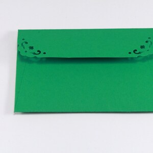 May include: A green envelope with a decorative, cut-out design on the top flap.