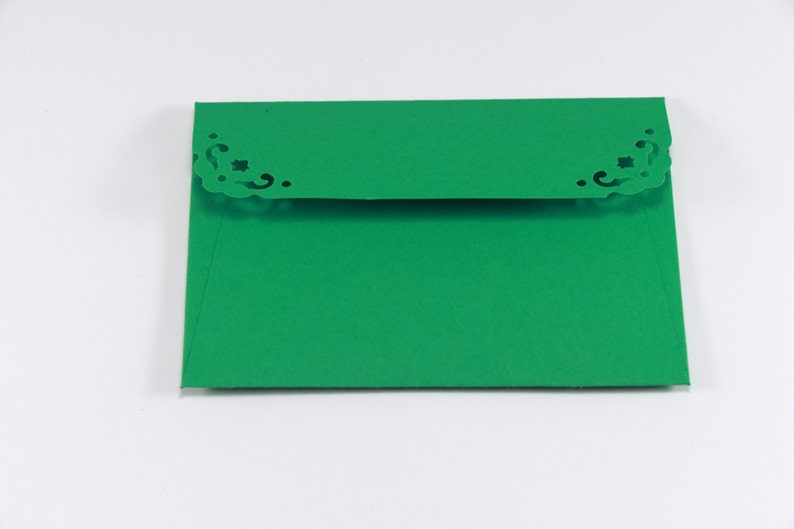 May include: A green envelope with a decorative, cut-out design on the top flap.