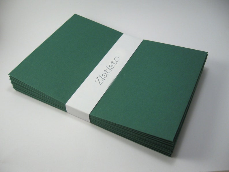 May include: A stack of dark green envelopes with a white label that says "Zlatisto" on it.