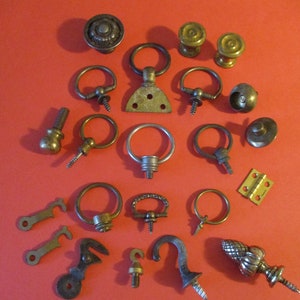 Puede incluir: Surtido de herrajes metálicos vintage, incluyendo ganchos, anillos, pomos y tiradores. Los herrajes son de diversas formas y tamaños, y algunos tienen un tornillo o clavo para su fijación.