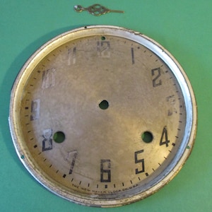 May include: A vintage clock face with black numbers and a silver background. The clock face is labeled "The New Haven Clock Co. U.S.A."