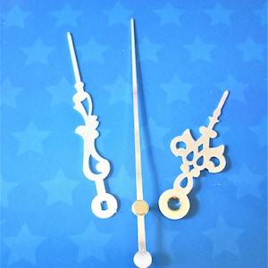 May include: Three silver clock hands with decorative cutouts. The hands are on a blue background with white stars.