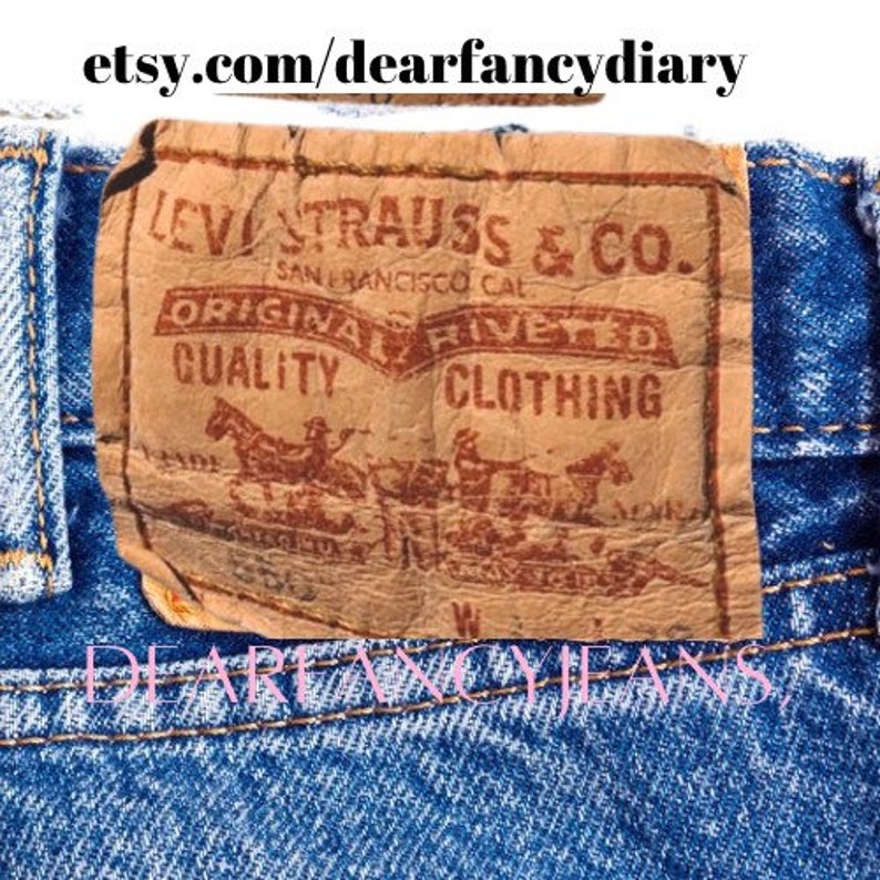 May include: A close-up of a brown leather Levi's patch with the text "Levi Strauss & Co. San Francisco Cal. Original  Riveted Quality Clothing" in red lettering. The patch is attached to a pair of blue denim jeans.