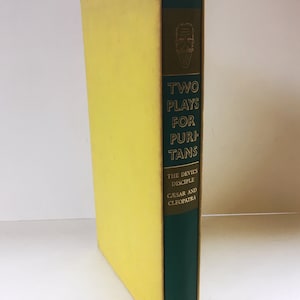 Könnte beinhalten: Ein gelbes und grünes Hardcover-Buch mit dem Titel "Two Plays for Puritans" mit dem Untertitel "The Devil's Disciple" und "Caesar and Cleopatra".