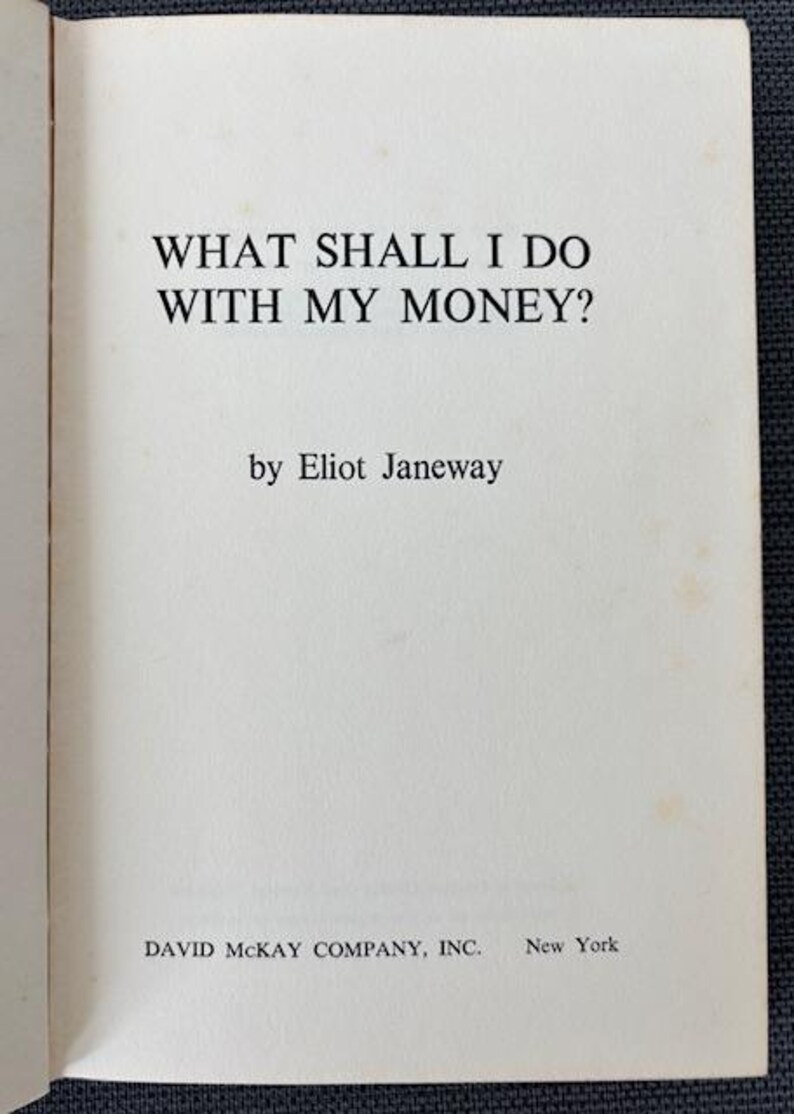 May include: Open book page with the title "WHAT SHALL I DO WITH MY MONEY?" by Eliot Janeway. The publisher is David McKay Company, Inc., New York. The text is in black font on an off-white page.