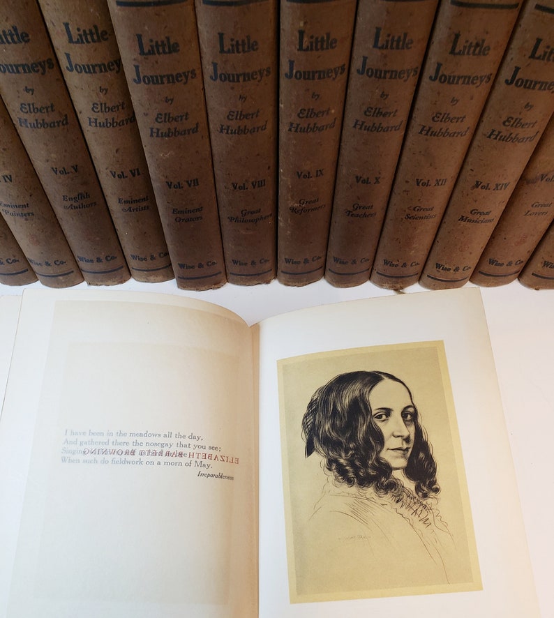 May include: An open book with a quote from the poem "Imparablene" by Emily Dickinson. The book is titled "Little Journeys" by Elbert Hubbard. The book is part of a set of books with the same title.