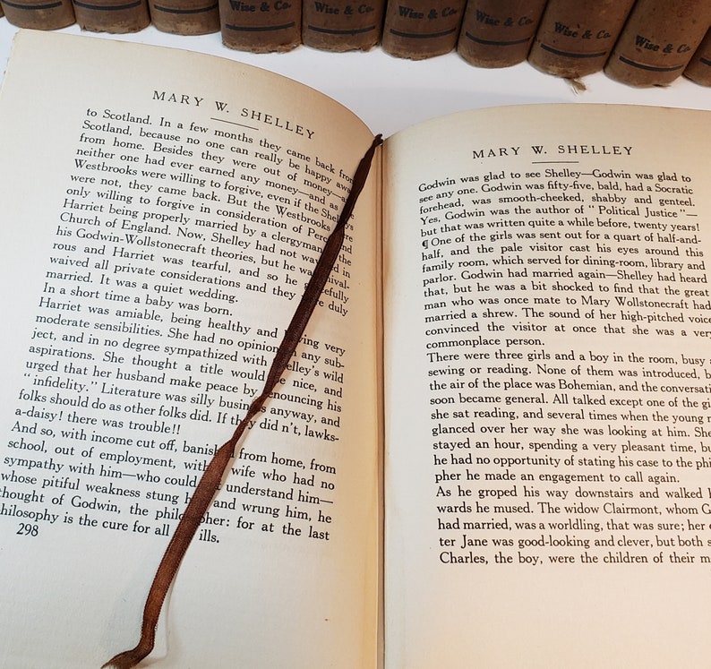 May include: An open book with a brown leather bookmark. The book is titled "Mary W. Shelley" and the text on the page discusses the life of Mary Shelley and her husband Percy Shelley. The book is part of a collection of books with the same title and author.