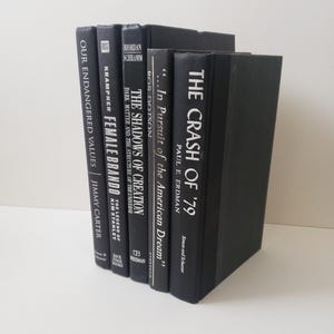 黒と銀のインスタント ライブラリ。冒険好きな読者や賢いスタイリストのためのビンテージ ブックのコレクション。ニュートラルな古い本のセット。
