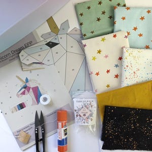 以下が含まれることがあります： ユニコーンのペーパーピーシングプロジェクト用クラフトキット。印刷されたパターン、星やスプラッター柄の緑、青、白、黄色、黒の布地、白い糸、金属製のハサミ、スティックのり、スレッドバームが含まれています。