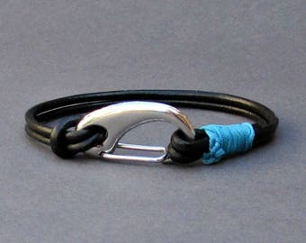 May include: A black leather bracelet with a silver clasp and a blue accent.