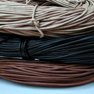 Puede incluir: Tres carretes de cord&oacute;n de cuero en diferentes colores: natural, negro y marr&oacute;n. Los cordones est&aacute;n enrollados apretados y listos para ser utilizados en proyectos de artesan&iacute;a.