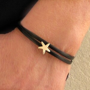 Peut inclure: Un bracelet en cuir noir avec un charme étoile en or.