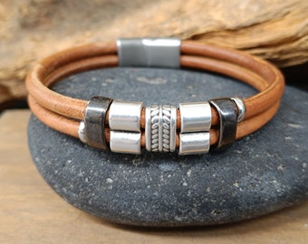 May include: A double-strand brown leather bracelet with silver and black metal beads. The bracelet has a magnetic clasp.