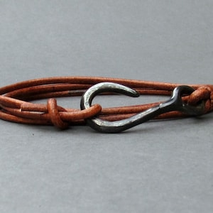 May include: A brown leather bracelet with a silver metal hook clasp.