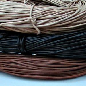 May include: Three spools of leather cord in different colors: natural, black, and brown. The cords are wound tightly together.