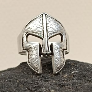 Op de afbeelding: Een zilveren ring met een gestructureerd ontwerp van een Spartaans helm.