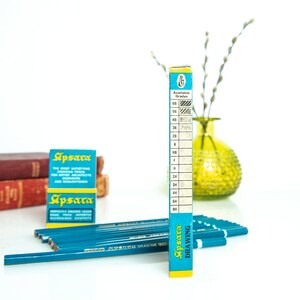 May include: A collection of Apsara drawing pencils and packaging. The pencils are teal with silver text, and the packaging is blue and yellow. The image includes a box displaying available grades, ranging from 6B to 8H.