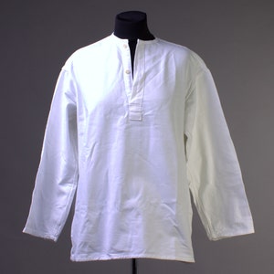 May include: A white long-sleeved shirt with a button-up collar and a single button closure at the neck.