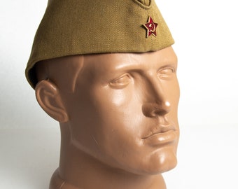 May include: A brown military style hat with a red star and hammer and sickle emblem.