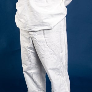 May include: A white long-sleeved shirt with a button-up collar and a white pair of pants. The person is wearing black shoes.