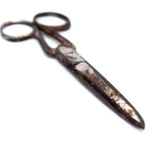 May include: Rusty metal scissors with a silver blade and a black handle. The scissors are isolated on a white background.