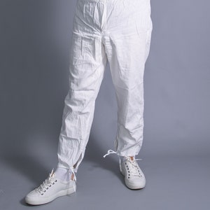 May include: White pants with a drawstring waist and tie closures at the ankles. The pants are made of a lightweight fabric and have a relaxed fit.