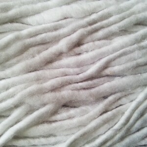 May include: Close-up of a white cotton yarn, showing the texture and fibers of the material.