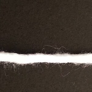 Puede incluir: Primer plano de una l&iacute;nea blanca dibujada sobre una superficie negra. La l&iacute;nea es ligeramente irregular y tiene una textura difusa.