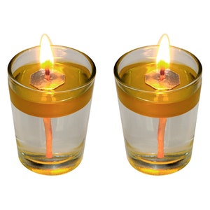 May include: Two clear glass candle holders with a yellow wax candle inside. The candles are lit and the flames are visible.