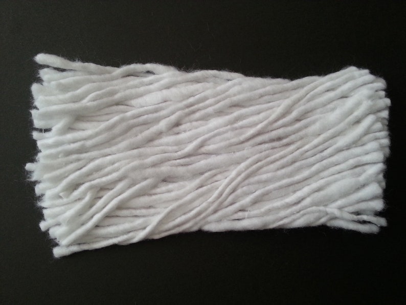 May include: A close-up of a white cotton mop head. The mop head is made of long, thin strands of cotton that are tightly packed together.