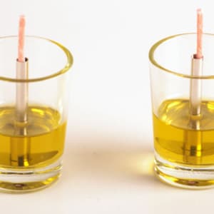 Peut inclure: Deux bocaux en verre transparent remplis de liquide jaune avec une mèche dans chaque bocal.