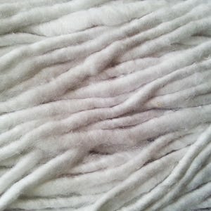 Puede incluir: Primer plano de un manojo de hilo de algod&oacute;n blanco, mostrando la textura suave y esponjosa de las fibras.