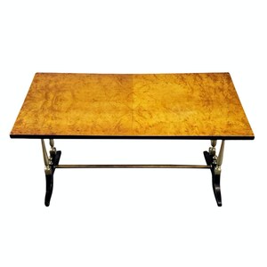 May include: A rectangular coffee table with a wood top and black and silver legs. The top has a wood grain pattern.