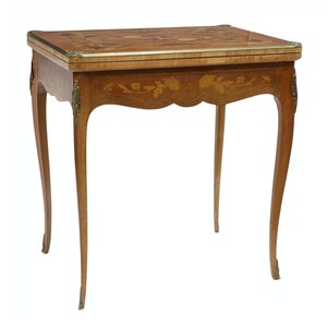 May include: A wooden game table with intricate marquetry inlay and brass accents. The table has a rectangular top and four cabriole legs.