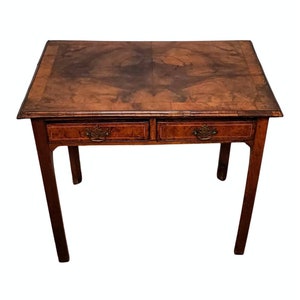 May include: A two-drawer wooden table with a brown wood top and brass drawer pulls. The table has four legs and is made of solid wood.