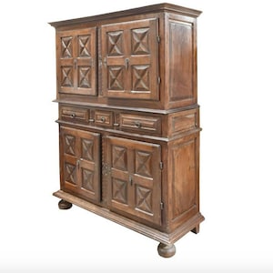 May include: A tall, antique wooden cabinet with two sets of double doors and three drawers. The doors and drawers have intricate carved designs.