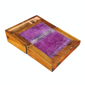 May include: A wooden writing desk with a hinged lid and a purple velvet interior. The desk has a brass lock and hinges.