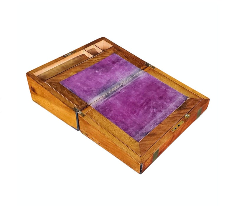 May include: A wooden writing desk with a hinged lid and a purple velvet interior. The desk has a brass lock and hinges.