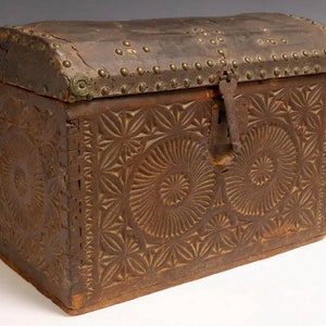 May include: A wooden chest with a leather lid, secured with metal studs and a lock. The chest is decorated with intricate carved designs.