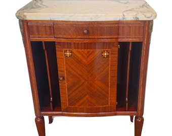 Puede incluir: Un gabinete de madera vintage con una tapa de mármol, un solo cajón y una puerta con una incrustación geométrica. El gabinete tiene un frente curvo y se apoya en cuatro patas.