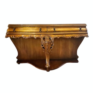 May include: A wooden wall shelf with two drawers and ornate carvings. The shelf is a rich brown color and has a curved design.